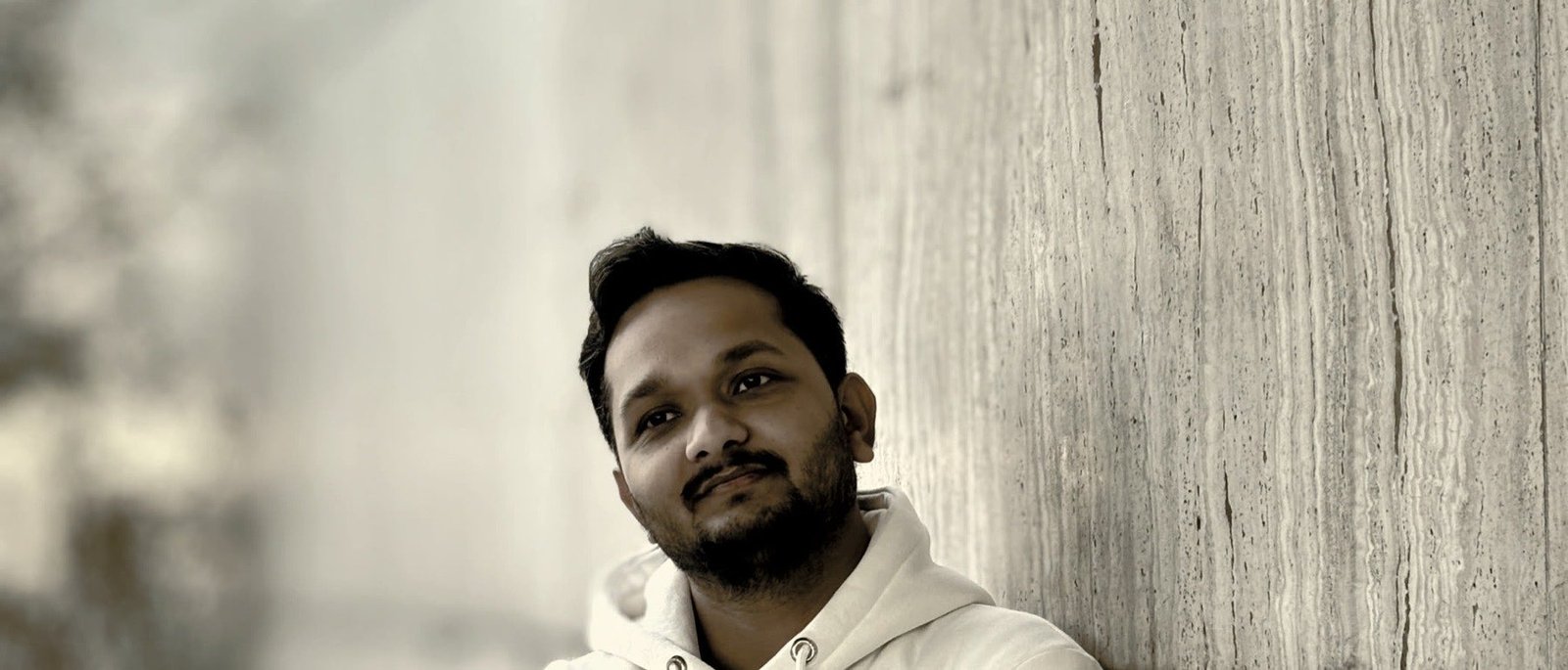 Akash Kumar, warm monochrome portrait against a marble wall